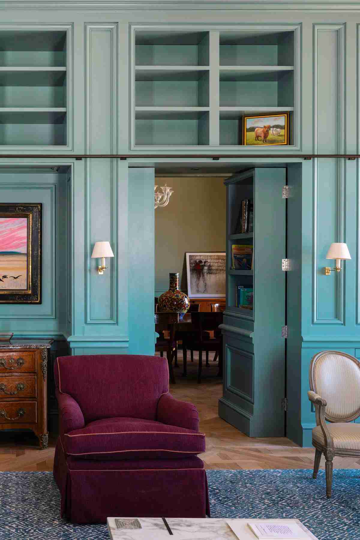 Luxurious living space featuring blue library cabinetry and secret doorway.