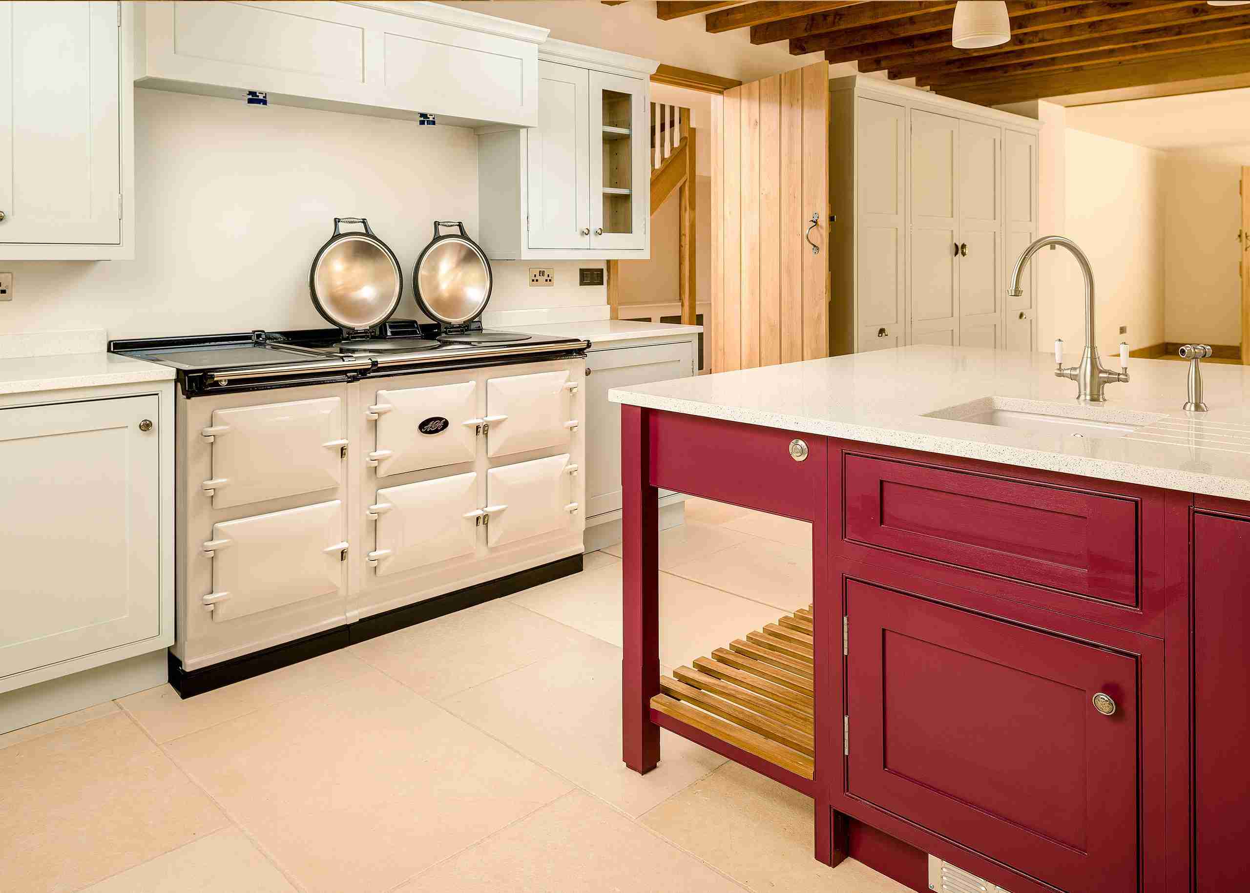 Shaker style kitchen featuring cream AGA and dark fuchsia island.