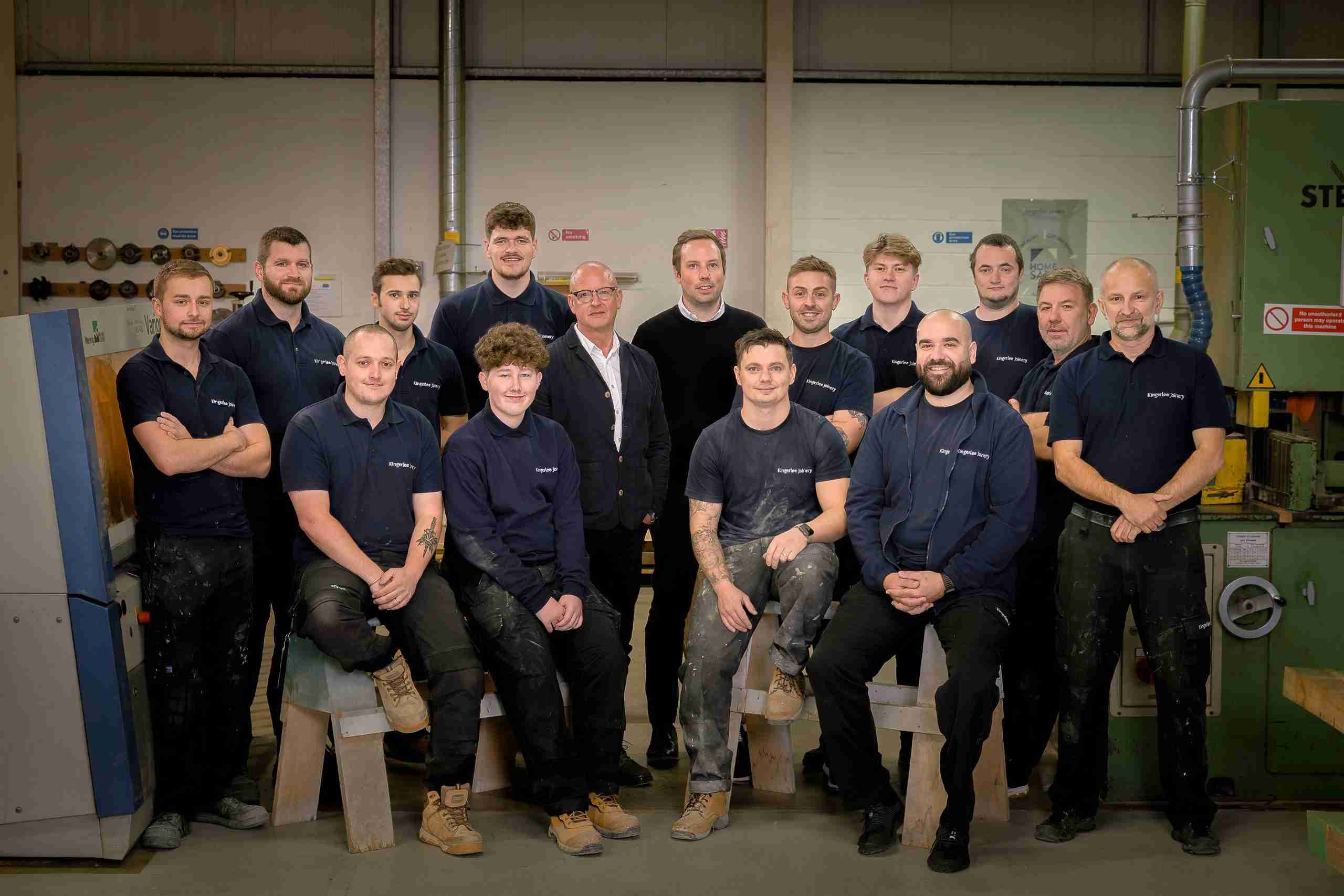 The Kingerlee Joinery team standing together in the workshop, surrounded by tools and timber, showcasing the people behind the craftsmanship.